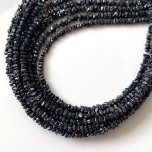 May include: A strand of black diamond beads. The beads are rough and irregular in shape, giving the strand a rustic look.