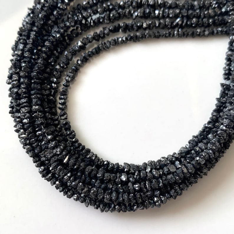 May include: A strand of black diamond beads. The beads are rough and irregular in shape, giving the strand a rustic look.