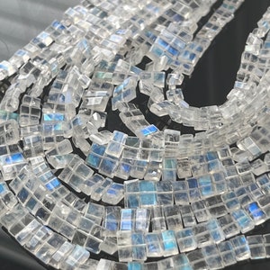May include: A strand of iridescent white moonstone beads, each bead is a square shape with a slightly rectangular form.