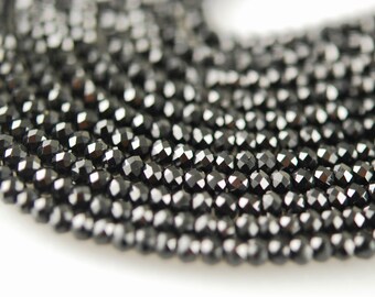 May include: A close-up of a strand of black faceted beads. The beads are small and round, and they have a shiny, reflective surface.