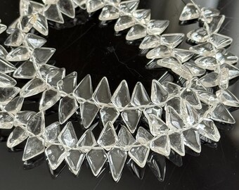 May include: Clear, faceted glass beads strung together to form a necklace or garland. The beads are triangular and arranged in a repeating pattern. The clear beads reflect light, creating a sparkling effect.