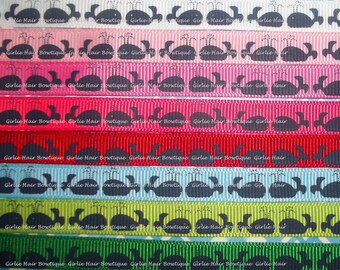 May include: Ten spools of ribbon with a whale design. The ribbon colors are white, pink, light pink, red, light blue, green, and dark green. The whales are black and have a water spout design. The ribbon is labeled "Girlie Hair Bowtique".
