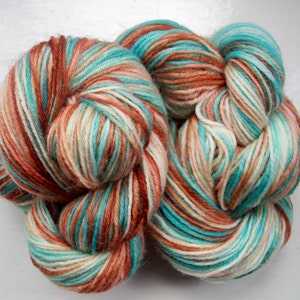 May include: A skein of yarn with a multi-colored pattern of teal, white, and orange.