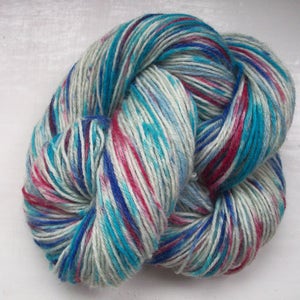 May include: A skein of colorful yarn with a mix of blue, teal, pink, and white fibers. The yarn is tightly wound, showing the texture and color variations. Ideal for knitting or crocheting projects.