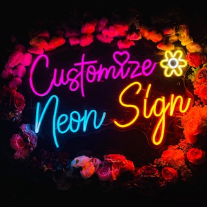 May include: A neon sign with the text "Customize Neon Sign" in pink, blue, and yellow. The sign is surrounded by red, pink, and white flowers.