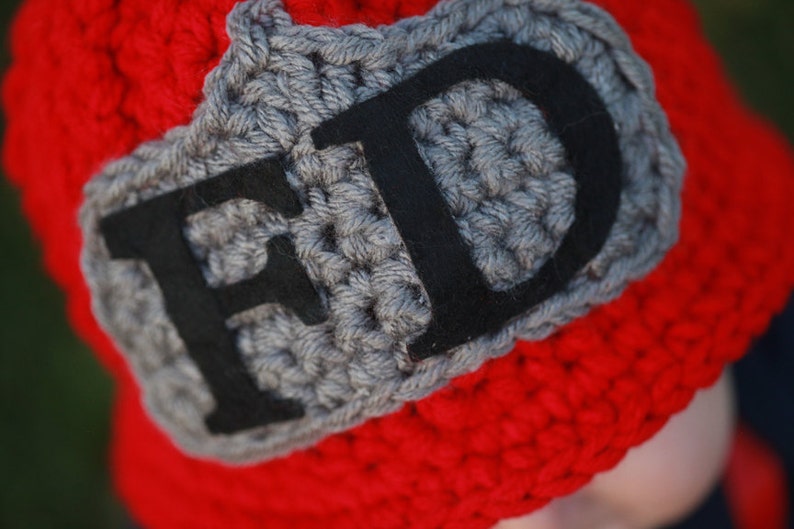 May include: Red crocheted hat with a gray crocheted patch that says "FD" in black felt letters.