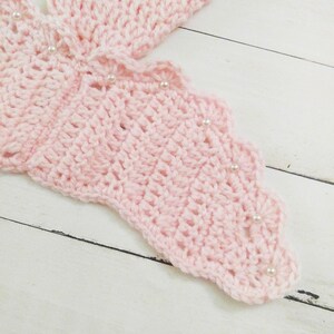 May include: Pink crocheted butterfly wing with white pearl embellishments.