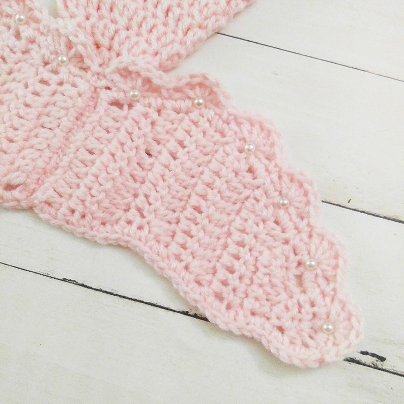 May include: Pink crocheted butterfly wing with white pearl embellishments.