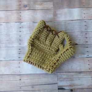 May include: A crocheted baseball glove in a light green color with brown stitching.