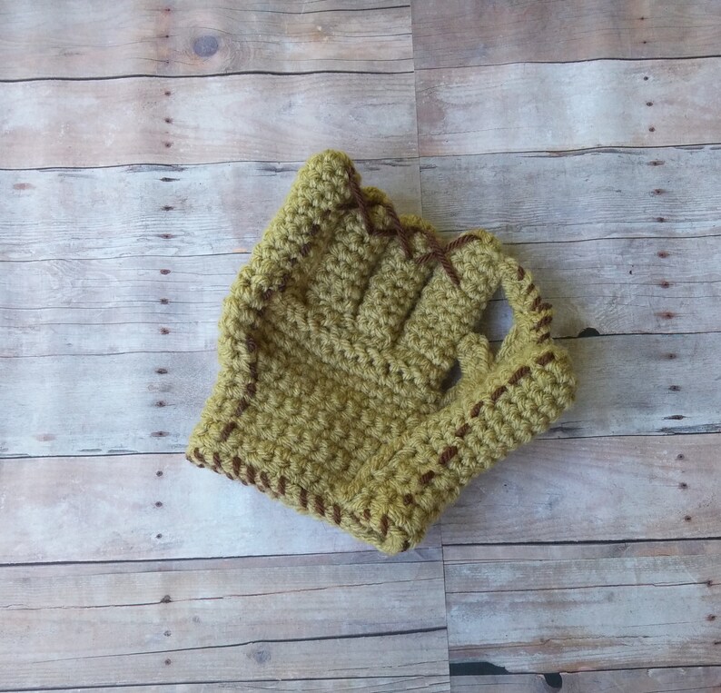May include: A crocheted baseball glove in a light green color with brown stitching.