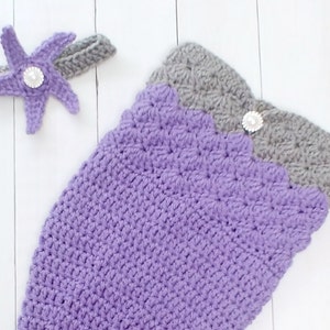 May include: A purple and gray crocheted mermaid tail costume with a matching purple starfish headband. The headband has a pearl embellishment.