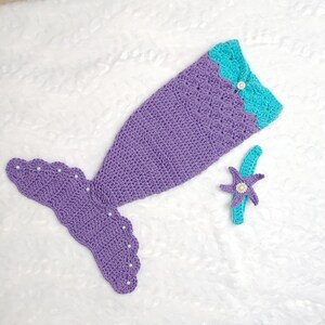 May include: Purple and turquoise crocheted mermaid tail costume with a matching headband featuring a starfish design. The tail has a scalloped edge and is decorated with white pearl beads.