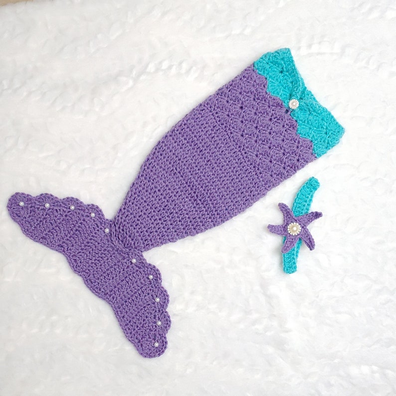 May include: Purple and turquoise crocheted mermaid tail costume with a matching headband featuring a starfish design. The tail has a scalloped edge and is decorated with white pearl beads.