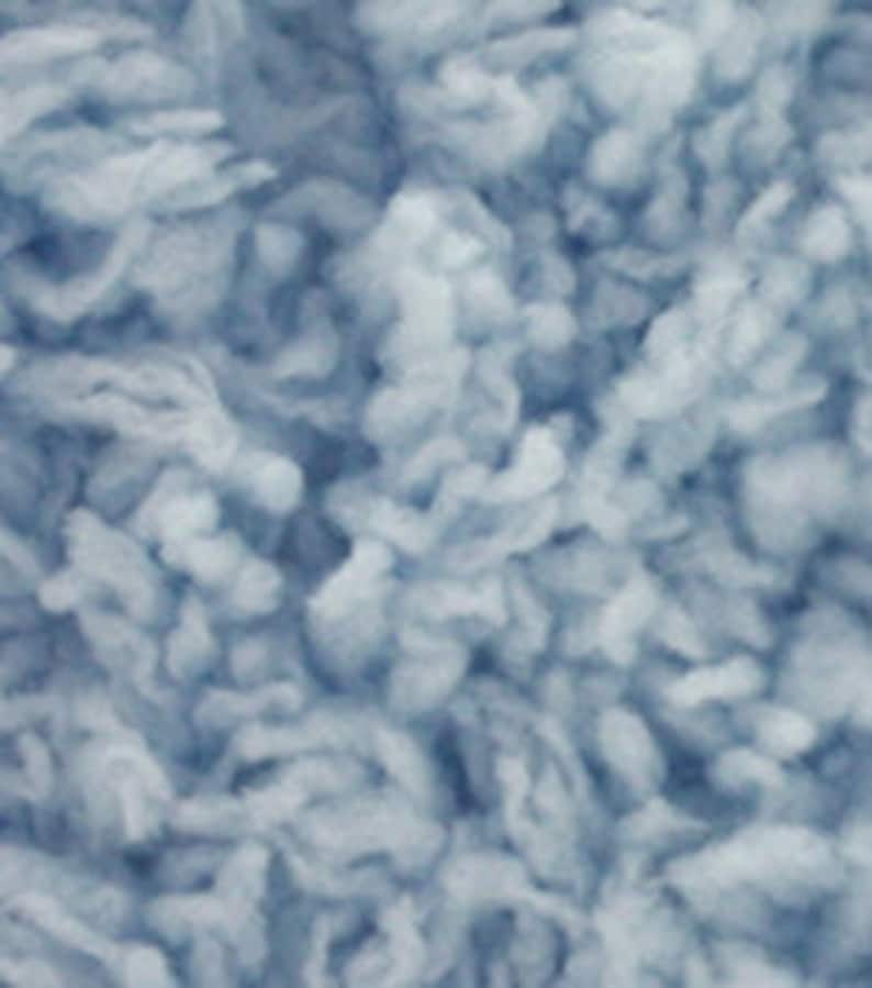 May include: A close-up of a light blue fluffy yarn. The yarn is soft and textured, ideal for knitting or crocheting.