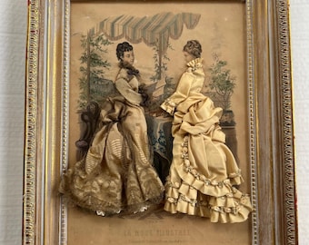 May include: A framed vintage print of two women in elaborate dresses, with the text "La Mode Illustree" at the bottom. The dresses are made of fabric and lace, and the print is in a gold frame.