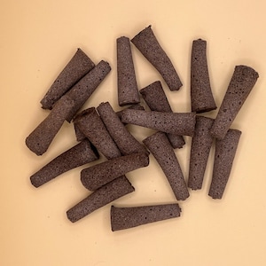 以下が含まれることがあります： ベージュの表面に置かれた、茶色の円錐形の線香の束