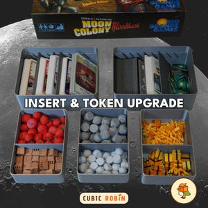 May include: A board game organizer with gray trays filled with game components. The trays hold cards, tokens, and other game pieces in various colors. The text "INSERT & TOKEN UPGRADE" is visible.
