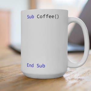 May include: White ceramic coffee mug with blue text that reads "Sub Coffee() End Sub".