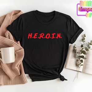 May include: Black t-shirt with the word "H.E.R.O.I.N." printed in red on the front.