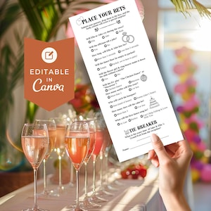 May include: A wedding game card with the text "Place Your Bets" is held near a row of champagne flutes filled with pink liquid. The card has questions about the wedding, with the words "Editable in Canva" on a brown background.