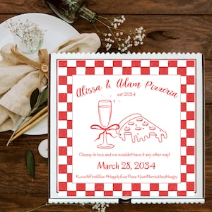 Può includere: Una scatola di pizza bianca con un motivo a scacchi rosso e bianco. La scatola ha un logo che dice "Alissa & Adam Pizzeria est 2034" con un bicchiere di champagne e una fetta di pizza. Il testo sotto dice "Cheesy in love and we wouldn't have it any other way! March 28, 2034 #LoveAtFirstSlice #HappilyEverPizza #JustMarriedAndHungry"