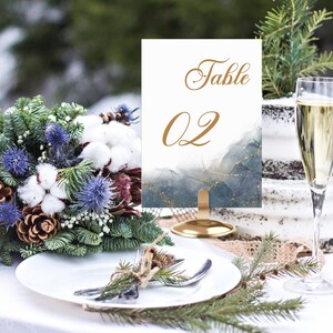 May include: A gold table number card with a blue and gold watercolour background. The card reads "Table 02" in gold lettering.