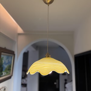 May include: A yellow and white striped glass pendant light with a scalloped edge.