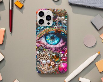 May include: A colorful phone case with a large blue eye and rhinestones. The eye is surrounded by gold and silver accents and a butterfly.