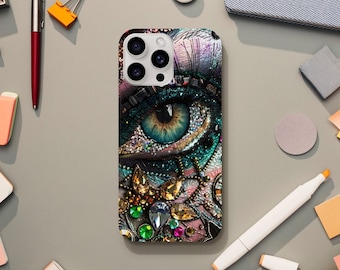 May include: A phone case with a colorful, abstract design featuring a large eye with rhinestones and a camera lens cutout.