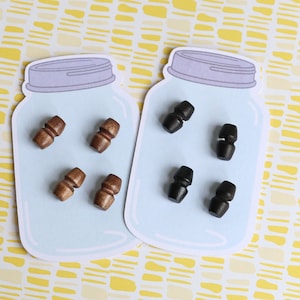 May include: Two mason jar-shaped cards with wooden toggles. One card has four brown toggles and the other has four black toggles.
