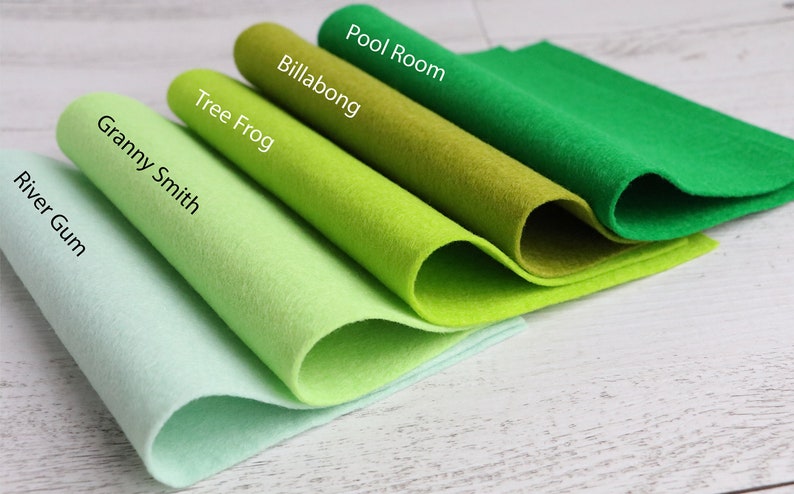 Puede incluir: Cinco muestras de tela de fieltro de diferentes tonos de verde, enrolladas y etiquetadas con nombres como "Pool Room", "Billabong", "Tree Frog", "Granny Smith" y "River Gum".