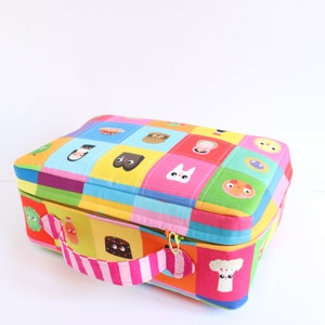 Puede incluir: Una bolsa de almuerzo colorida con cierre de cremallera y un asa a rayas rosa y blanca. La bolsa est&aacute; hecha de tela acolchada y presenta una variedad de personajes de dibujos animados y dise&ntilde;os.