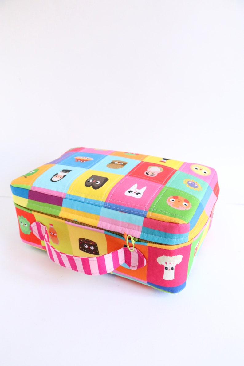 Puede incluir: Una bolsa de almuerzo colorida con cierre de cremallera y un asa a rayas rosa y blanca. La bolsa est&aacute; hecha de tela acolchada y presenta una variedad de personajes de dibujos animados y dise&ntilde;os.