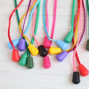 May include: A selection of brightly coloured pull cords, each with a teardrop-shaped toggle. The cords are in shades of red, green, yellow, pink, purple, and blue. The toggles are also in a variety of colours.
