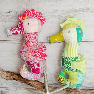May include: Two handmade patchwork seahorse toys. One is pink and white with floral patterns and the other is green and white with stripes and floral patterns.