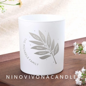 May include: A white candle holder with a gray leaf design and the names Alexa, Milo, Rebecca, Noah, Daddy, and Mummy. The text "THE MICHAELS FAMILY" is printed on the side. The brand name "NINOVIVONACANDLES" is printed at the bottom.