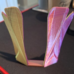 May include: A pair of decorative, geometric, 3D printed wall shelves. One shelf is a light wood color and the other is a light pink color.