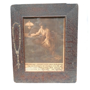 May include: An antique framed print featuring a woman in a dress, seated near a lamp. The frame is dark wood with a decorative rosary attached to the side. Text at the bottom reads, "THE HOURS I SPENT WITH THEE DEAR HEART ARE AS A STRING OF PEARLS TO ME."
