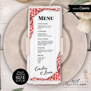 May include: A white menu card with red and white gingham trim. The menu card has a rustic wood background and lists the appetizers, starters, main course, dessert, and drinks for a wedding reception. The menu card is titled "MENU" and includes the names "Emilia & Liam".