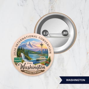 May include: A round pinback button featuring a colorful illustration of a mountain, a waterfall, a tower, and a boat. The text reads 2026 INTERNATIONAL CONVENTION from Washington WITH ALL OUR LOVE. The back shows a metal pin mechanism.