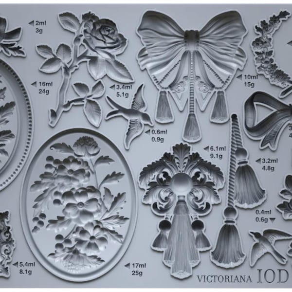 May include: A light gray silicone mold sheet labeled Victoriana IOD featuring various recessed designs including oval frames, floral arrangements, bows, tassels, birds, and decorative borders, each with printed volume and weight measurements.