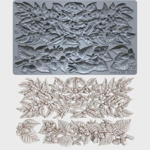 May include: A grey silicone mold featuring intricate botanical relief designs of leaves, berries, and nuts. The mold includes text labels indicating capacities of 52ml/78g, 36ml/54g, and 7.4ml/11g, with the brand name Hazel & Bay IOD printed in the corner.