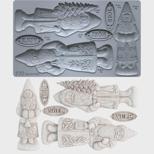 May include: A gray silicone mold sheet featuring recessed designs of two distinct Santa figures, one holding a tree and one holding a lantern, along with three oval plaques embossed with the words JOIE, NOEL, and YULE, plus IOD BELSNICKEL text.