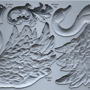 May include: A gray silicone mold featuring swan and decorative scroll designs. The mold includes two swan halves, a swan head, and several ornate scroll elements. Measurements are provided in milliliters and grams.