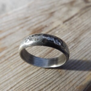 May include: A silver hammered wedding band with a matte finish.