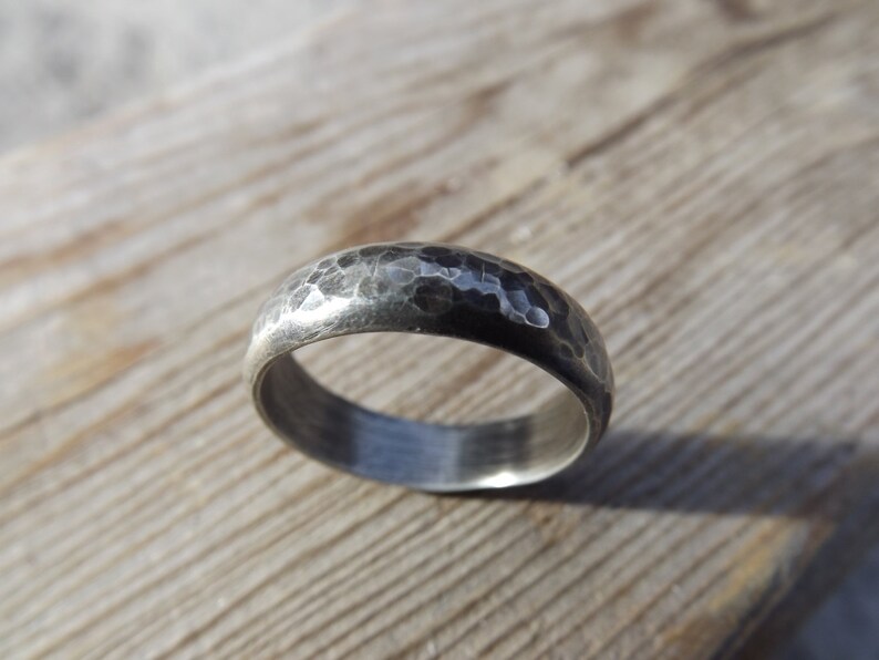May include: A silver hammered wedding band with a matte finish.