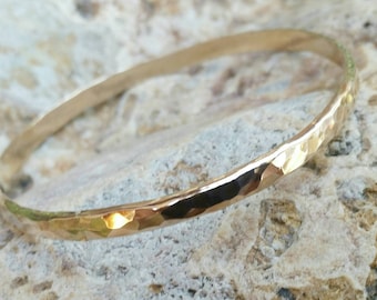 Brazalete de oro grueso y ancho con textura brillante martillada. Disponible en oro laminado o oro de 14 kt. Incluye grabado.