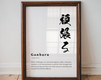 May include: A framed wall art print featuring the Japanese kanji for Ganbaru in black ink, followed by the word Ganbaru, the label - japanese, and a paragraph of English text defining the term as the determination to persist with strength.