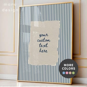 May include: A vertical rectangular wall art print in a thin gold frame featuring a blue and white vertical striped background. Centered is a beige, torn-edge paper overlay with the dark blue handwritten text your custom text here.