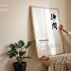 May include: A rectangular wall art print in a light wood frame featuring the Japanese kanji for Nakama, the word Nakama, and a definition text describing a bond formed through shared goals, loyalty, and mutual support. The text maru design is visible.